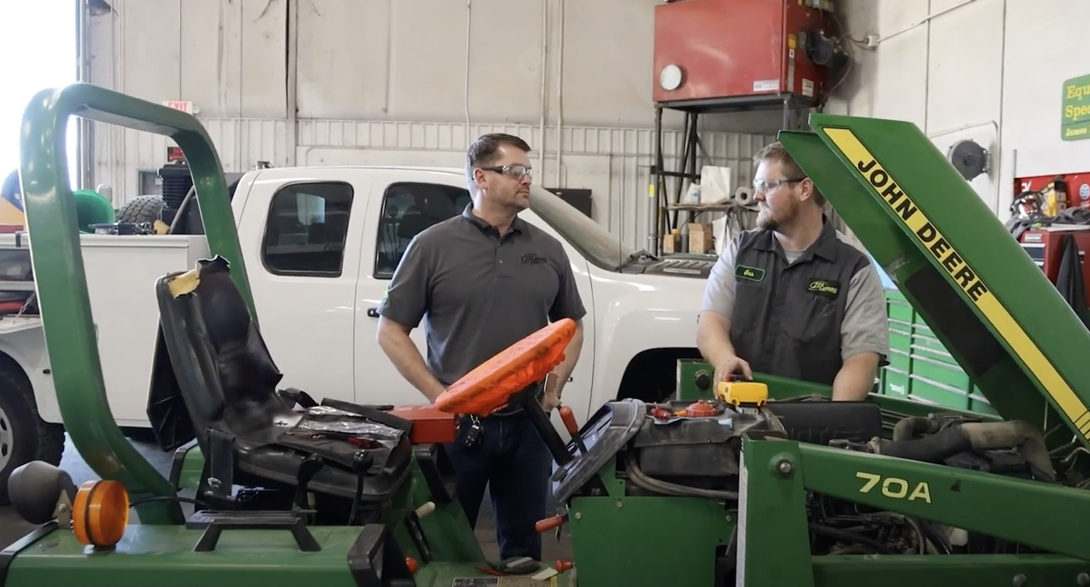 Two 21st Century Equipment employees working on a piece of machinery.